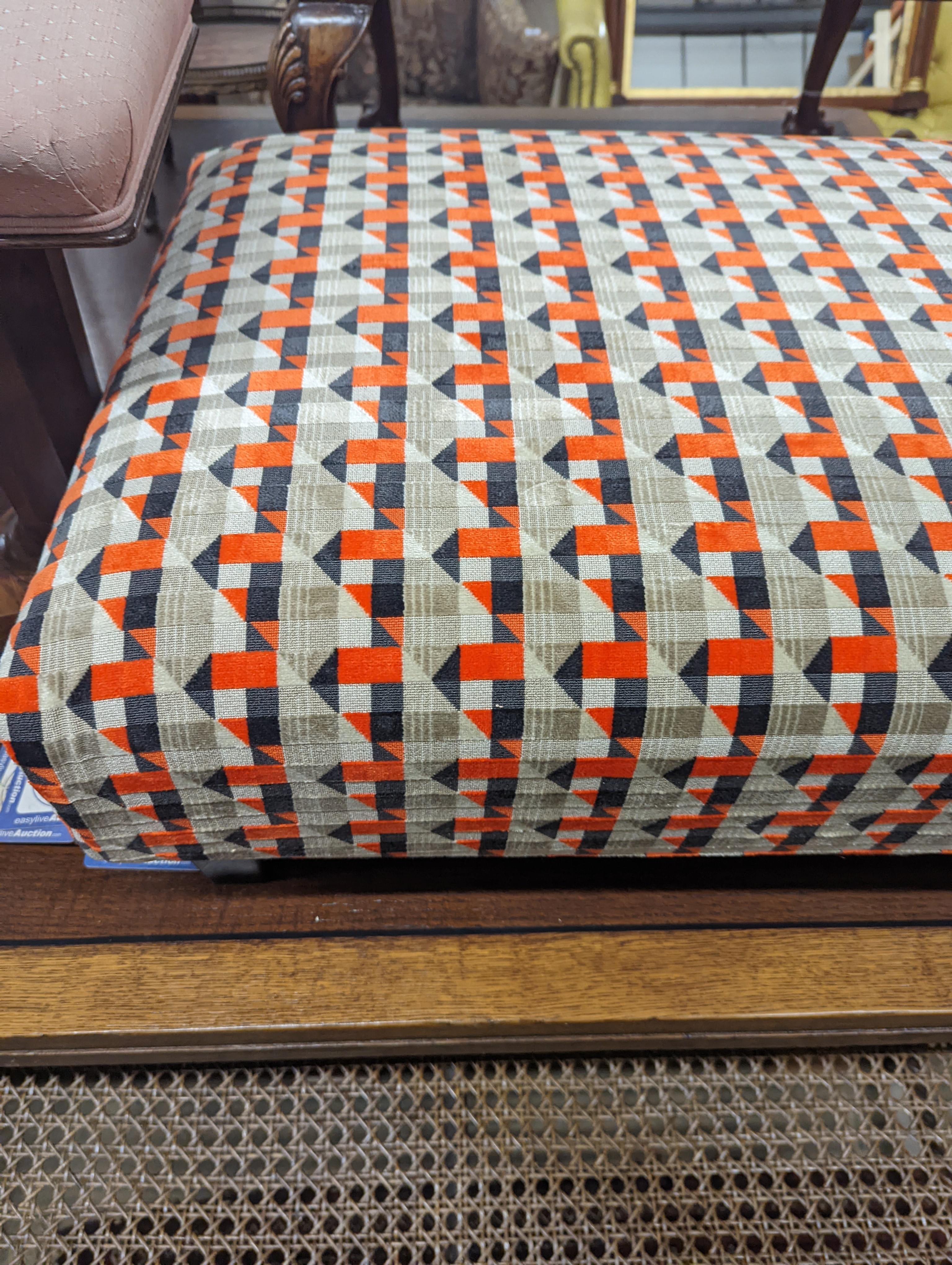 A contemporary rectangular footstool upholstered in Romo 